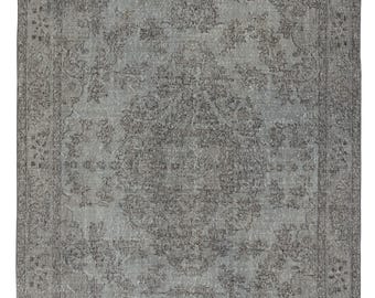 Op de afbeelding: Een rechthoekig, grijs vintage vloerkleed met een ingewikkeld bloemmotief. Het vloerkleed heeft een centraal medaillonontwerp en een gedetailleerde rand. Het kleurenpalet is voornamelijk grijs met subtiele tintvariaties, wat een versleten uiterlijk creëert.