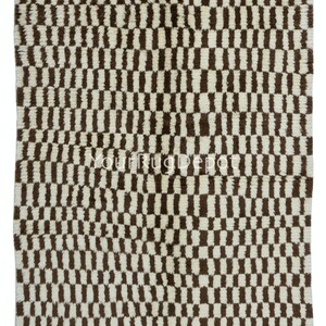 May include: A white and brown checkered rug with a geometric pattern. The rug is made of a soft, fluffy material.