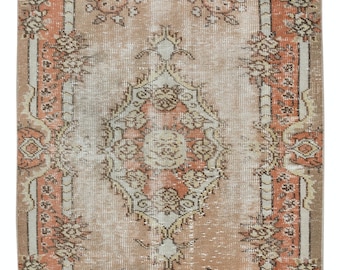 May include: A vintage rug with a faded floral pattern in shades of beige, peach, and cream. The rug has a distressed look and a worn border.