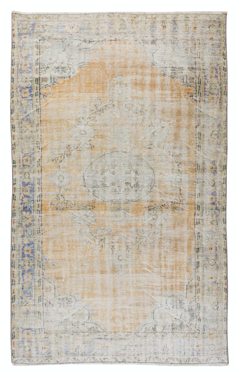 May include: A vintage rug with a faded floral pattern in shades of blue, green, and beige. The rug has a distressed look and a worn border.