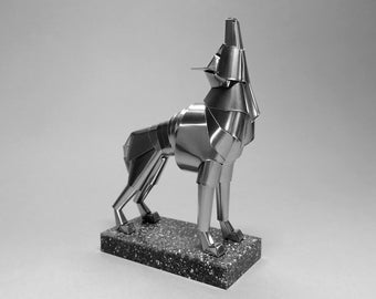 May include: A silver metal sculpture of a wolf howling, standing on a textured gray base.