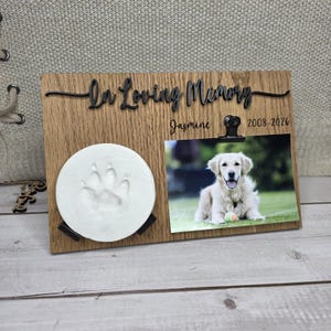 Puede incluir: Marco conmemorativo de madera para mascotas con las palabras "In Loving Memory" y una foto de un golden retriever. Incluye una huella de pata y el nombre "Jasmine" con los años 2008-2026.