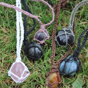 May include: Five different crystal necklaces with various stones, including amethyst, black obsidian, rose quartz, carnelian, and labradorite. Each stone is wrapped in a macrame knot.