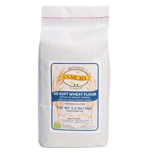 May include: A white bag of "00 Soft Wheat Flour" from Molino CA.ME.MA, with a blue and white label. The label states the net weight is 2.2 lbs (1kg). The flour is ideal for pizza, bread, or pasta and contains gluten.