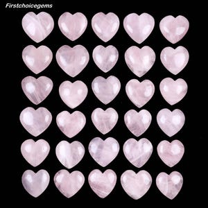 Pode incluir: Uma coleção de pedras em forma de coração de quartzo rosa. As pedras são de um rosa suave com tons variados e veios naturais. Os corações estão dispostos em um padrão de grade contra um fundo preto. O texto "firstchoicegems" está no canto superior esquerdo.