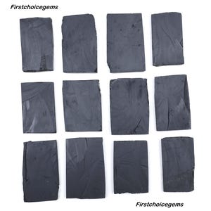 Puede incluir: Doce losas rectangulares de piedra preciosa gris oscuro dispuestas en una cuadrícula. Las piedras tienen bordes irregulares y una superficie ligeramente texturizada. La imagen es una vista superior, mostrando las variaciones naturales.