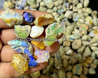 Puede incluir: Una colección de piedras preciosas de ópalo en bruto de varios colores y tamaños. Los ópalos son una mezcla de blanco, marrón, verde, azul y naranja. Los ópalos están en una mano, y el fondo es un montón de más ópalos.