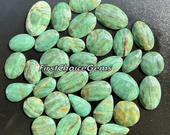Könnte beinhalten: Eine Sammlung von 25 grünen und braunen Edelstein-Cabochons. Die Steine sind oval geformt und haben eine glatte, polierte Oberfläche.  FirstChoiceGems ist auf dem Bild gedruckt.