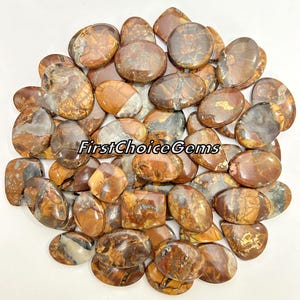 May include: A collection of 25 brown, tan, and white agate gemstone cabochons. The cabochons are oval shaped and have a polished finish.  FirstChoiceGems.