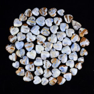 Puede incluir: Una colección de piedras en forma de corazón azules y marrones. Las piedras están dispuestas en círculo sobre un fondo negro.