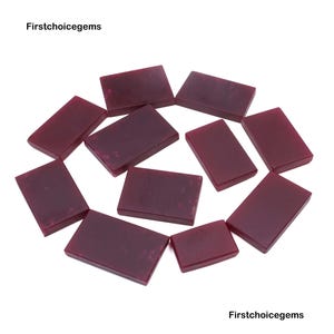 Può includere: Una collezione di gemme rettangolari color bordeaux disposte su sfondo bianco. Le gemme sono lisce e lucide, con un colore intenso e ricco. Il testo "Firstchoicegems" è visibile nell'immagine.