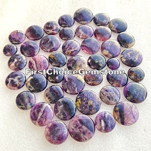 May include: A collection of 25 round, flat, purple and gold fluorite cabochons. The cabochons are smooth and polished, with a variety of patterns and swirls.