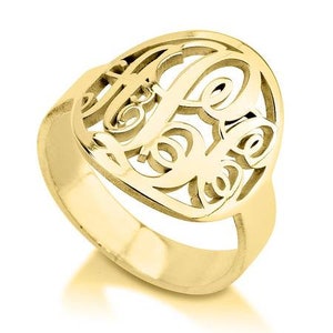 K&ouml;nnte beinhalten: Ein goldener Ring mit einem Monogramm-Design. Der Ring ist aus einem einzigen St&uuml;ck Metall gefertigt und hat eine glatte, polierte Oberfl&auml;che.