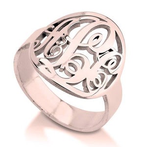 K&ouml;nnte beinhalten: Ein Ring aus Ros&eacute;gold mit einem Monogramm-Design. Der Ring ist aus Metall und hat eine glatte Oberfl&auml;che.