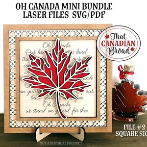 Op de afbeelding: Een vierkant houten bord met een lasergesneden ontwerp van een rood esdoornblad en de tekst van "Oh Canada". Het bord staat op een kleine houten standaard. De tekst "That Canadian Bread" staat in een rode cirkel boven het bord. De tekst "FILE #2 SQUARE SIGN" staat onder het bord.