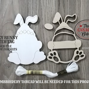 Puede incluir: Dos formas de conejo de madera sin terminar para un proyecto de artesan&iacute;a de etiqueta de Pascua peculiar. Las formas de conejo est&aacute;n listas para ser pintadas o decoradas. El texto "Quirky Bunny Easter Tag" y "Laser File SVG/PDF Formats" est&aacute; impreso en la madera. Se incluye hilo de bordar blanco.
