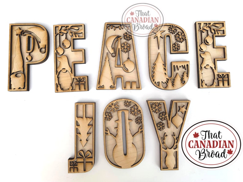 May include: Wooden cutout letters spelling "PEACE JOY" with various Christmas-themed designs inside each letter. The letters are on a white background.