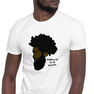 May include: White t-shirt with a black and brown illustration of a man's head with an afro and beard. The text "shifting my fro & behavior" is printed on the shirt.