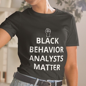 May include: Black t-shirt with a white raised fist and the text "Black Behavior Analysts Matter".