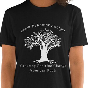 May include: Black t-shirt with a white tree graphic and the text "Black Behavior Analyst Creating Positive Change from our Roots".