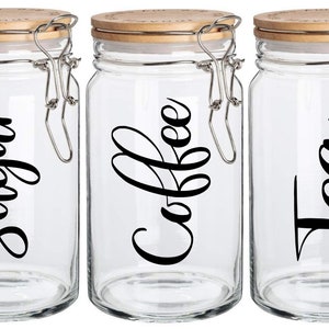 May include: Three glass jars with bamboo lids and silver clasps. The jars are labelled "Sugar", "Coffee", and "Tea" in black cursive lettering.