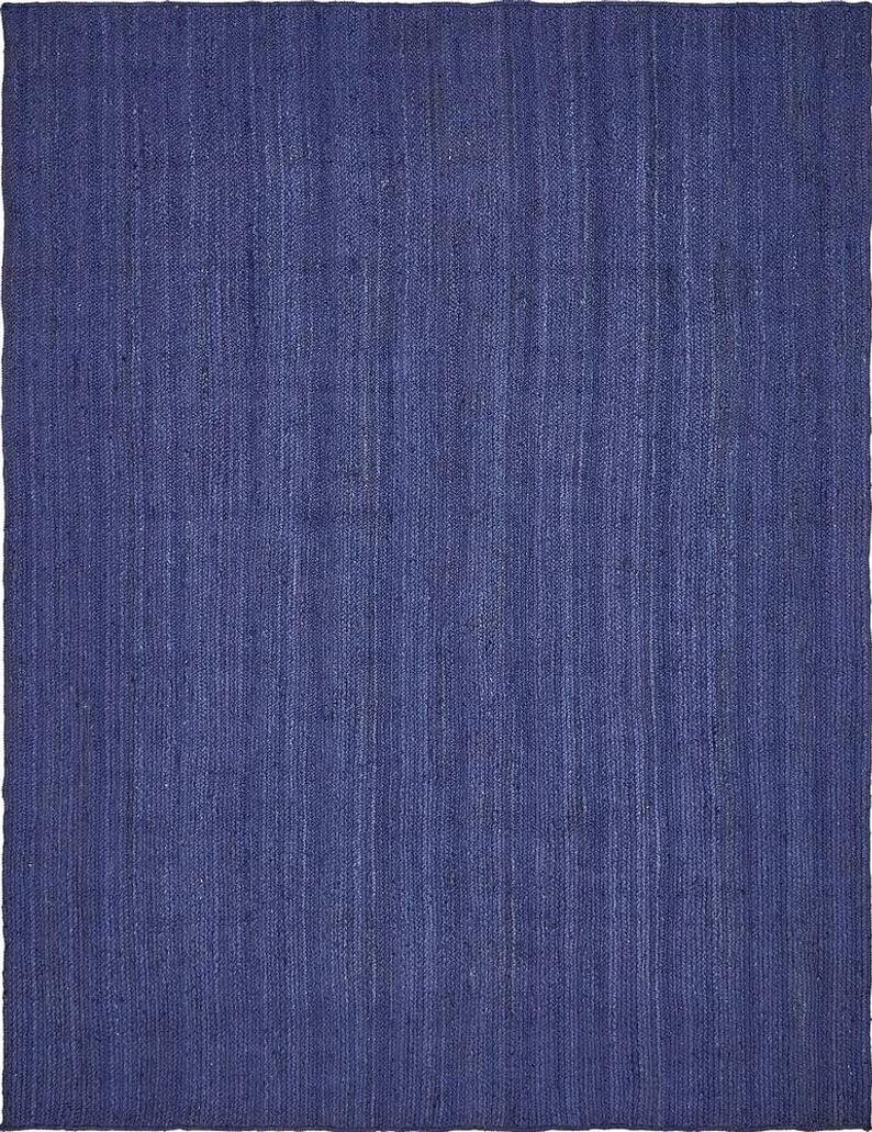 May include: A solid blue rug made of woven jute fibers. The rug has a subtle texture and a slightly distressed look.