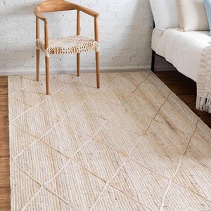 May include: A natural fiber rug with a diamond pattern woven into the design. The rug is a light beige color and has a subtle texture.