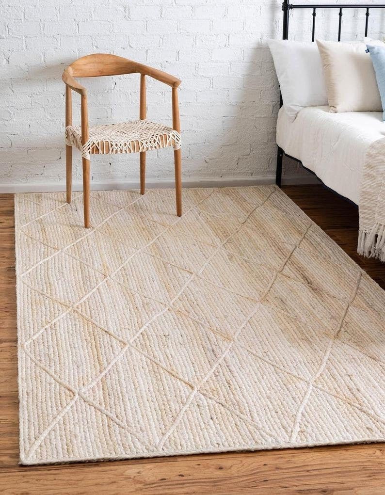 May include: A natural fiber rug with a diamond pattern woven into the design. The rug is a light beige color and has a subtle texture.