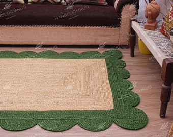 Könnte beinhalten: Ein rechteckiger Jute-Teppich mit grünem, gewelltem Rand. Der Teppich ist aus Naturfasern gefertigt und hat eine hellbraune Farbe.