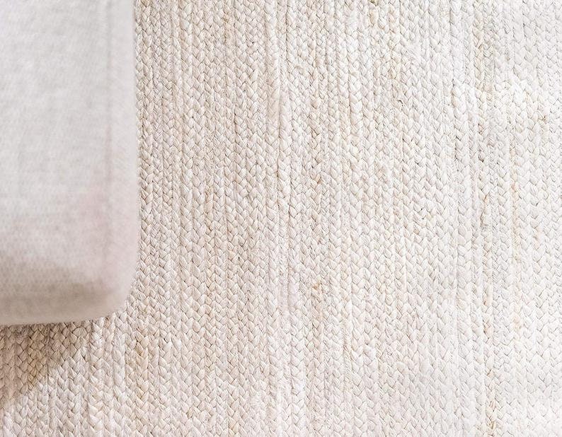 May include: A close-up of a white woven rug with a textured surface.