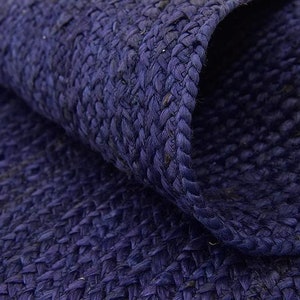May include: Close-up of a dark blue woven rug made of natural fibers. The rug has a textured surface and a slightly rough feel.
