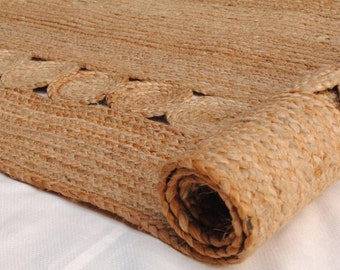 Könnte beinhalten: Ein Naturfaser-Teppich aus Jute mit einem gewebten Muster und einem gewellten Rand. Der Teppich ist aufgerollt und zeigt die Textur und Farbe des Materials.