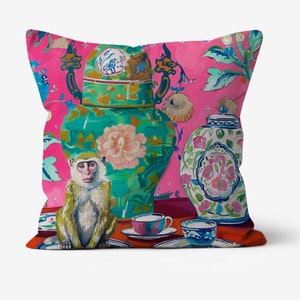 Peut inclure: Un coussin de canapé rose avec une illustration colorée d'un singe, deux vases ornés et des tasses à thé sur une table. Les vases sont décorés de motifs floraux et les tasses à thé sont sur des soucoupes.