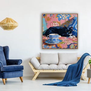 May include: An interior scene featuring a framed painting of a black cat resting on a floral patterned surface, with a blue and white teacup. A blue armchair, a wooden sofa, and a blue blanket are also visible.