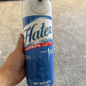 Puede incluir: Un vaso azul y blanco con las palabras "Haters be gone" y "Kills 99.9% of two-face haters". El vaso también presenta un logotipo de diablo azul y el texto "Don't mess with the boys scent."