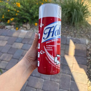May include: A red and white 20 oz tumbler with the text "Hat" in a blue script font. The tumbler reads "Kills 99.9%" and "Eliminates Chiefs Haters". The design includes a Chiefs logo and the phrase "Don't mess with the box".