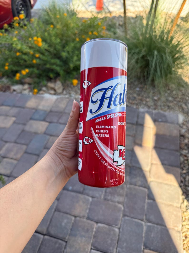 May include: A red and white 20 oz tumbler with the text "Hat" in a blue script font. The tumbler reads "Kills 99.9%" and "Eliminates Chiefs Haters". The design includes a Chiefs logo and the phrase "Don't mess with the box".
