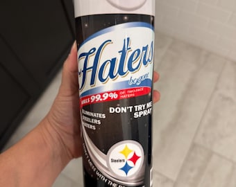May include: A stainless steel tumbler with a white top and a black body. The tumbler features the words "Haters be gone" and "Don't try me spray". The design includes the Steelers logo and the text "Eliminates Steelers Haters".