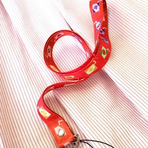 May include: A red lanyard with a white and red pattern of juice boxes. The lanyard has a silver clip and a black string.