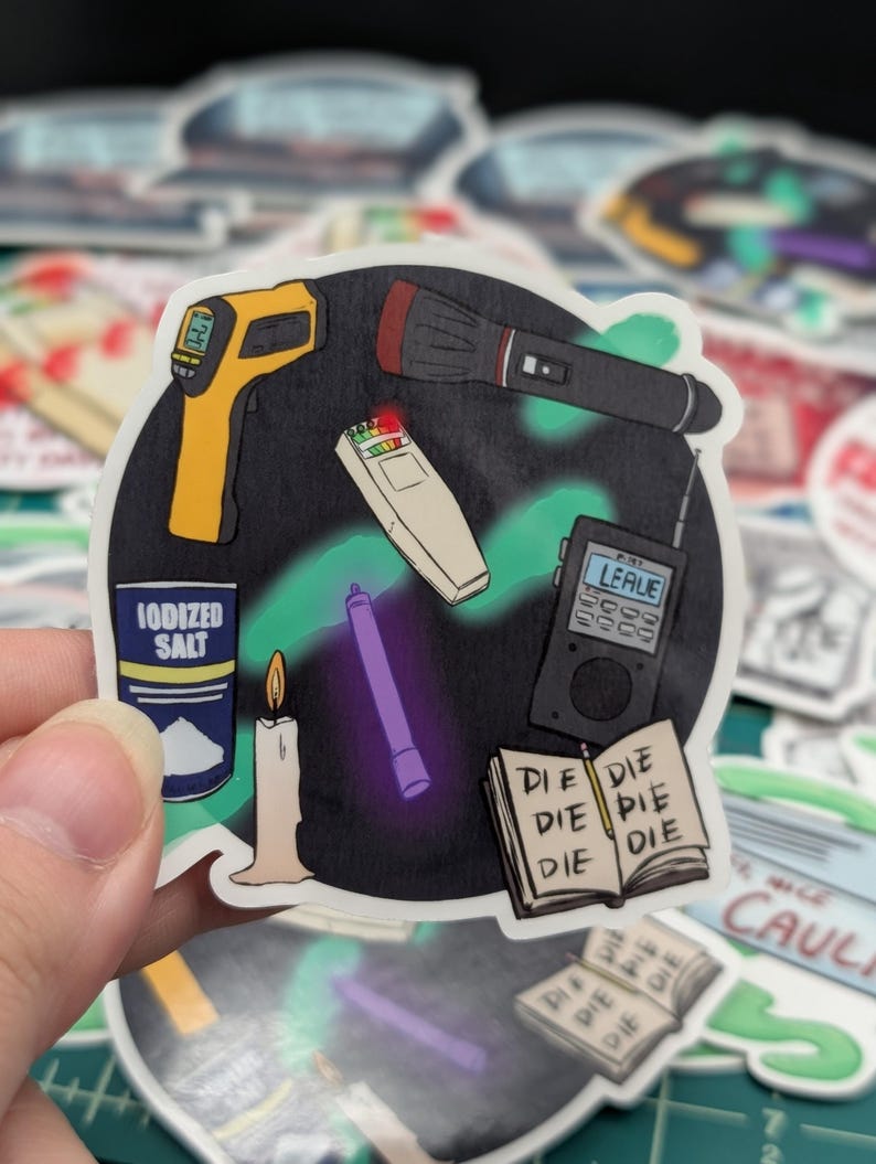 May include: A sticker featuring a collection of ghost hunting tools, including a flashlight, a thermometer, a candle, a spirit box, a UV light, and a container of iodized salt. The sticker also includes a notebook with the word "DIE" written on each page.