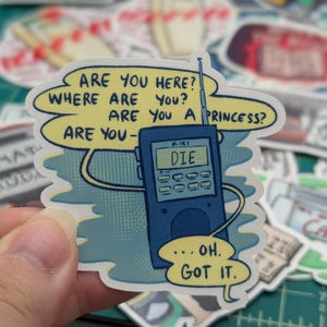 May include: A blue and white sticker with a cartoon illustration of a walkie-talkie with the text "ARE YOU HERE? WHERE ARE YOU? ARE YOU A PRINCESS? ARE YOU- DIE ...OH. GOT IT."