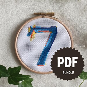 Könnte beinhalten: Ein Kreuzstich-Stickrahmen mit einem blauen und gelben Siebener-Design. Der Rahmen ist aus Holz und hat einen weißen Stoffhintergrund. Der Text "PDF BUNDLE" befindet sich auf einem schwarzen runden Aufkleber.