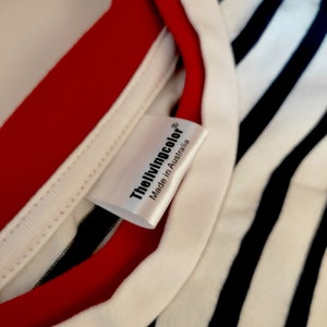 May include: White label with black text that reads "Thelivingcolor® Made in Australia" on a white and black striped shirt with a red trim.