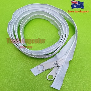 May include: White zipper tape with a white zipper pull. The zipper tape is coiled and the zipper pull is attached to the end of the tape.
