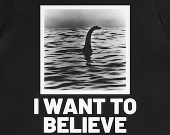 May include: Black t-shirt with a black and white photo of a creature in the water. The text "I WANT TO BELIEVE" is printed in white below the photo.