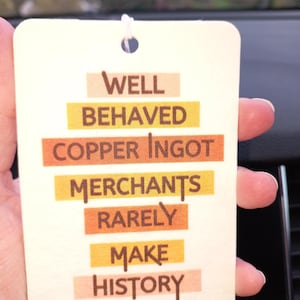 May include: A white card with the text "Well Behaved Copper Ingot Merchants Rarely Make History" printed in brown letters on colorful stripes.