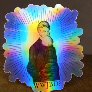 Puede incluir: Una pegatina holográfica con un retrato de un hombre con barba y el texto "WWJBD?" en una fuente arcoíris.