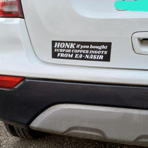 May include: A black rectangular bumper sticker on a white car with the text "HONK if you bought SUBPAR COPPER INGOTS FROM EA-NASIR" in white font.