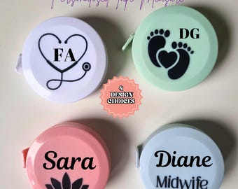 May include: Four personalized tape measures with different designs. The first is white with a stethoscope and the letters "FA". The second is light green with two footprints and a heart, and the letters "DG". The third is pink with a lotus flower and the name "Sara". The fourth is light blue with the name "Diane Midwife".