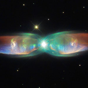 May include: A vibrant, colorful nebula in the shape of a butterfly, with a bright star at its center. The nebula is surrounded by a dark, starry background.